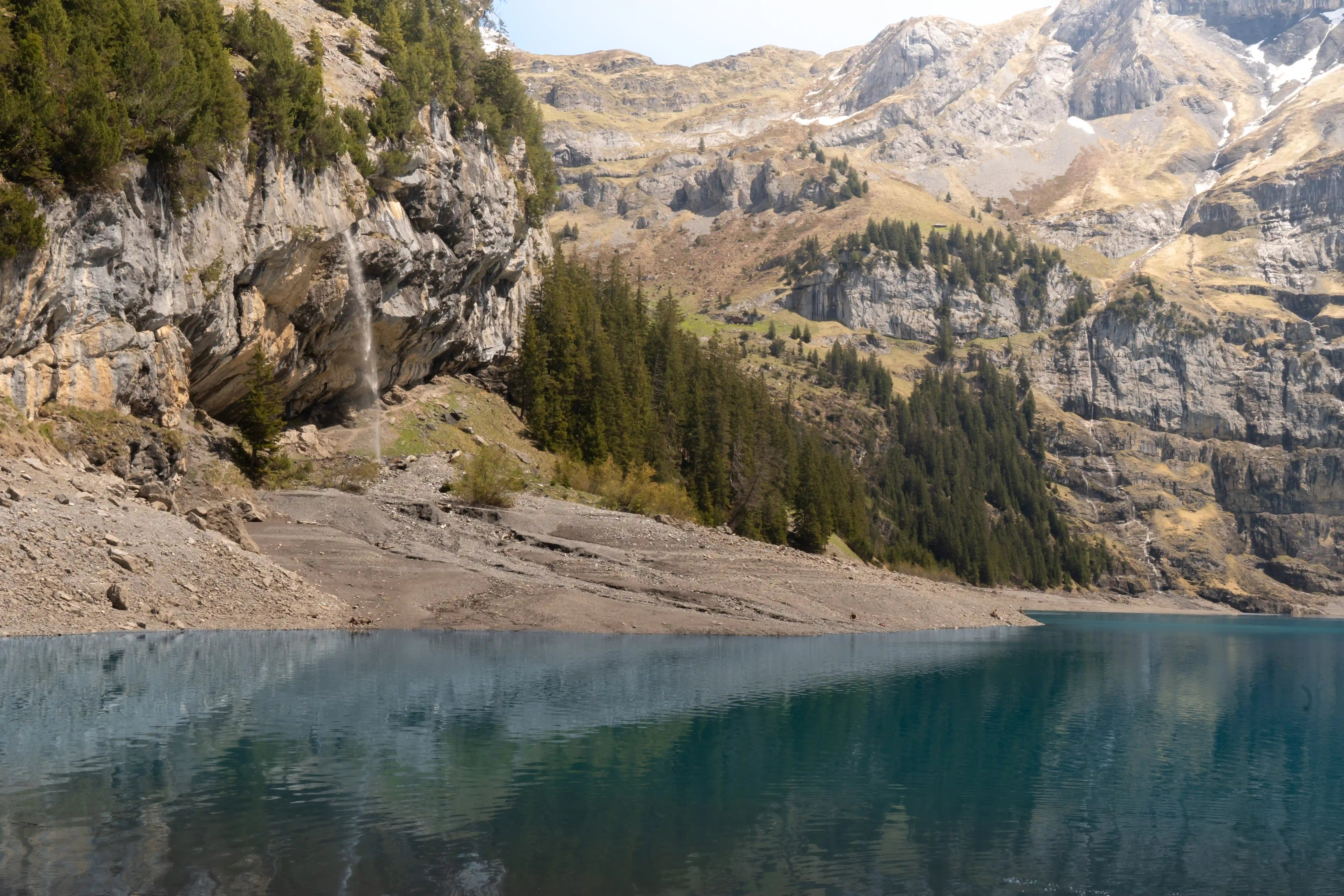 Waterfall cascading down rocky cliff face to blue lake.