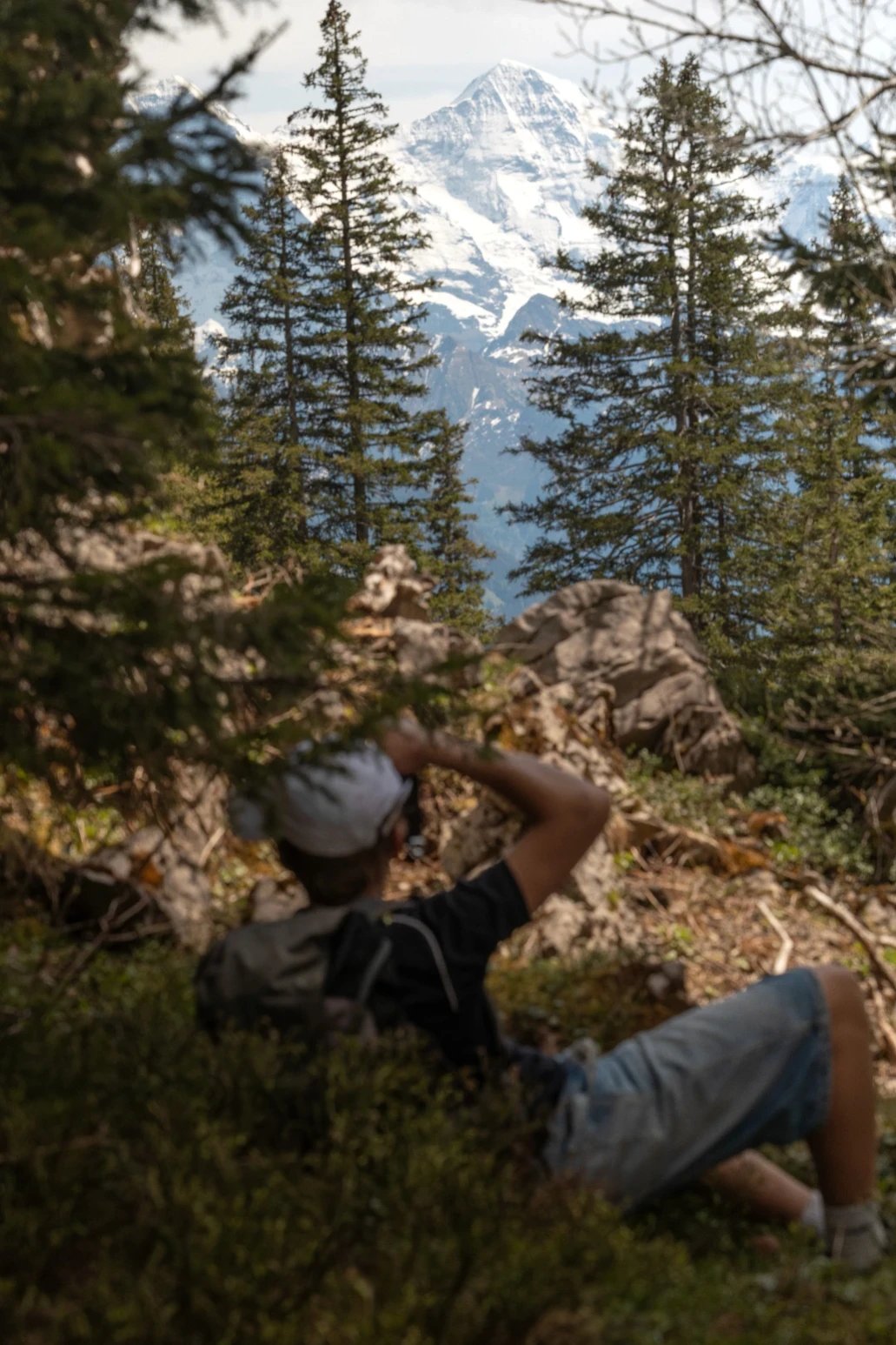 Person wearing cap takes photo of snowy mountains.